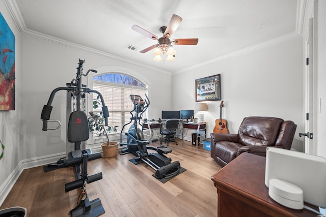 workout area with a ceiling fan, baseboards, wood finished floors, visible vents, and ornamental molding