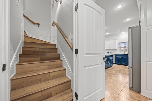 stairway featuring visible vents, ornamental molding, tile patterned floors, and recessed lighting