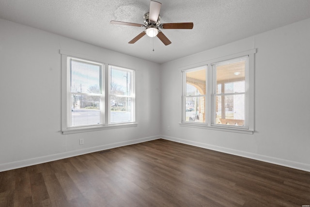 empty room with a textured ceiling, a healthy amount of sunlight, and dark wood-style floors