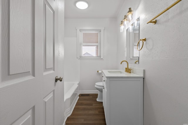 bathroom featuring vanity, wood finished floors, visible vents, a tub, and toilet