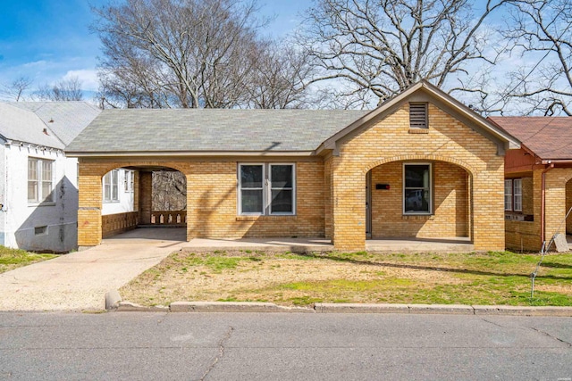 view of front of home featuring brick siding, covered porch, concrete driveway, and a carport