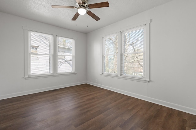 unfurnished room with dark wood-style floors, visible vents, a textured ceiling, and baseboards