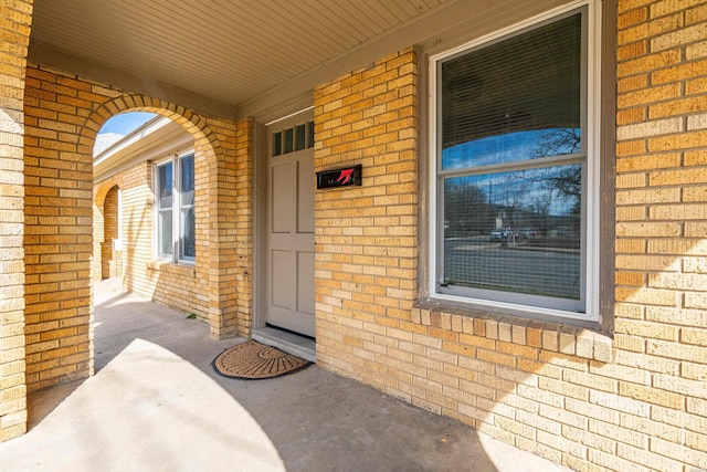 entrance to property featuring brick siding and covered porch