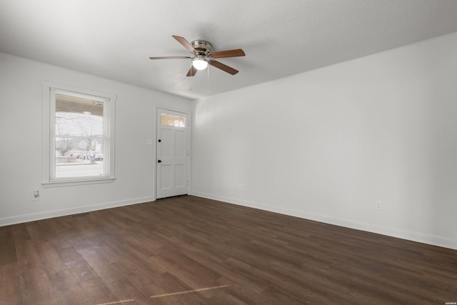 interior space with a ceiling fan, dark wood-type flooring, baseboards, and visible vents