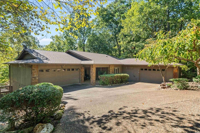 ranch-style house with aphalt driveway, a shingled roof, and an attached garage