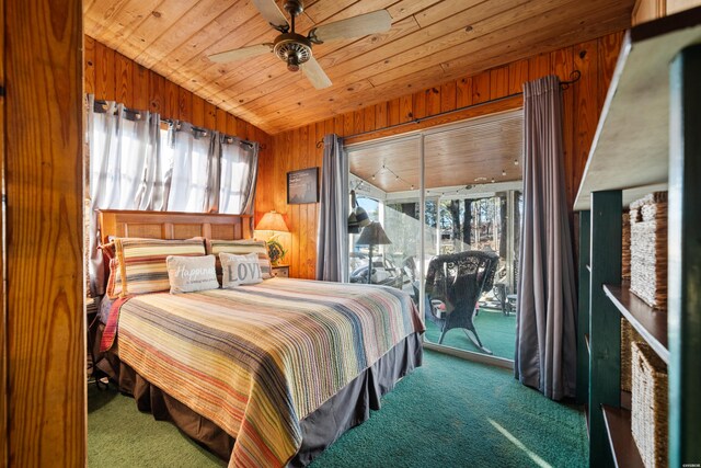 bedroom with a ceiling fan, wooden ceiling, access to outside, dark colored carpet, and wood walls