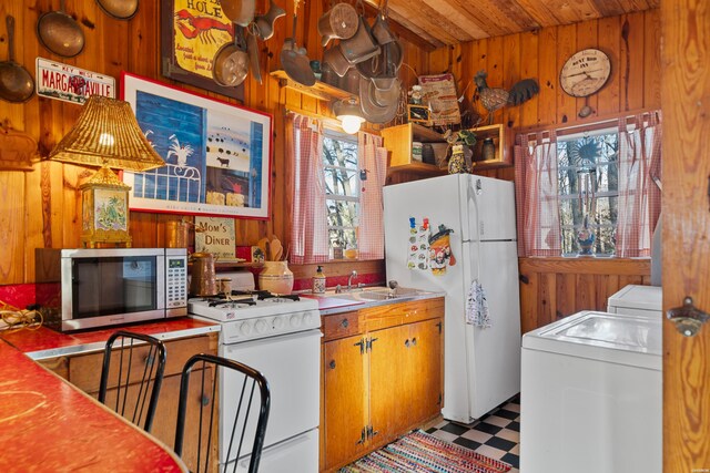 kitchen with washer / clothes dryer, white appliances, wood walls, and light floors