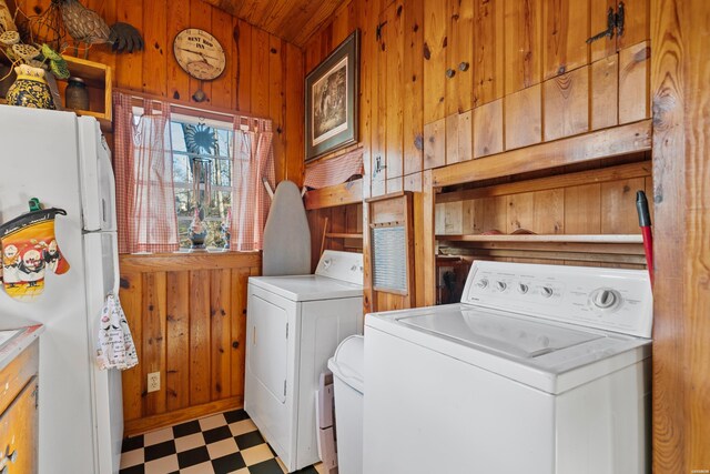 laundry area with light floors, independent washer and dryer, laundry area, and wood walls