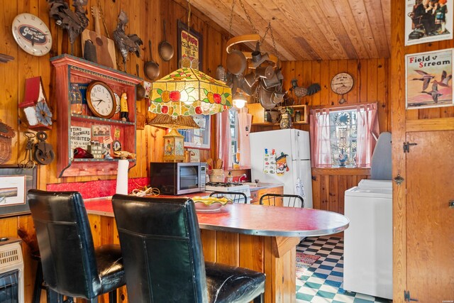 kitchen featuring wood walls, stainless steel microwave, and freestanding refrigerator