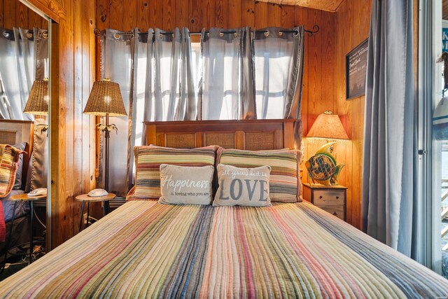 bedroom featuring wood walls and multiple windows