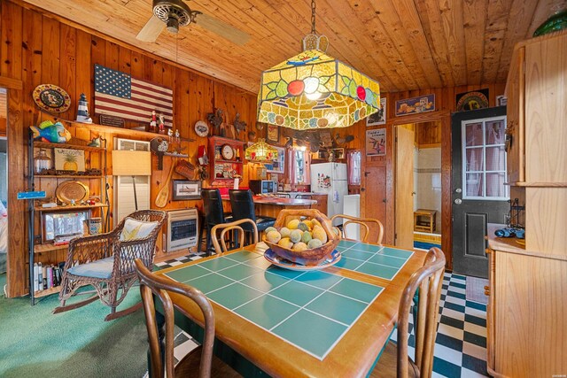 dining room featuring wooden walls, wooden ceiling, ceiling fan, heating unit, and carpet