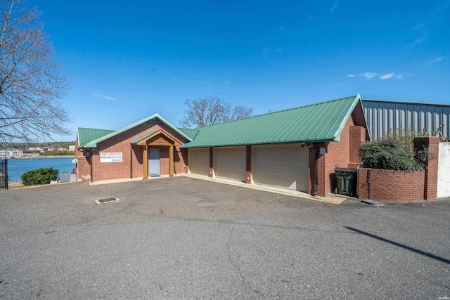 view of front of house with a water view, metal roof, an outdoor structure, and brick siding