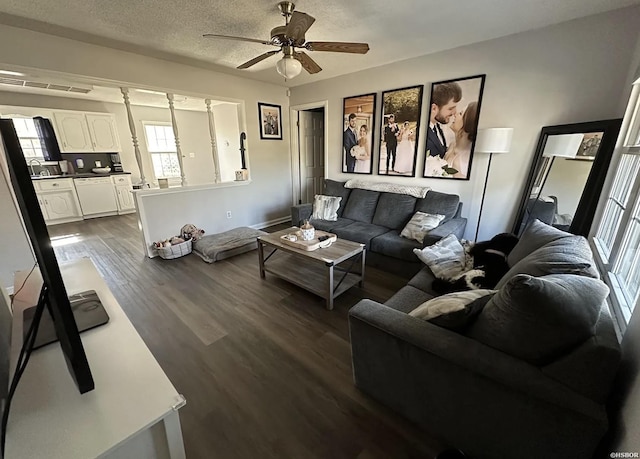 living area with visible vents, a ceiling fan, dark wood finished floors, and a textured ceiling