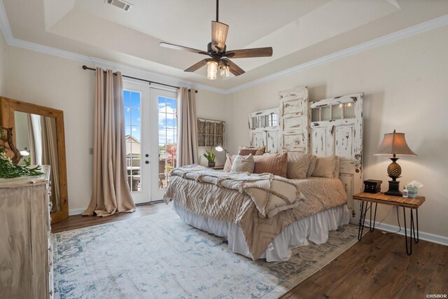 bedroom with access to exterior, a raised ceiling, french doors, and wood finished floors