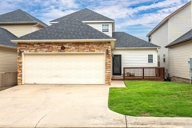 view of front of home featuring a shingled roof, concrete driveway, stone siding, an attached garage, and a front yard