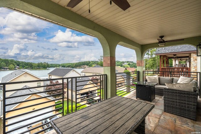 deck with ceiling fan, a water view, and an outdoor living space