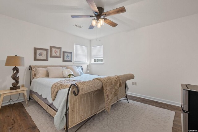 bedroom with visible vents, ceiling fan, baseboards, and wood finished floors