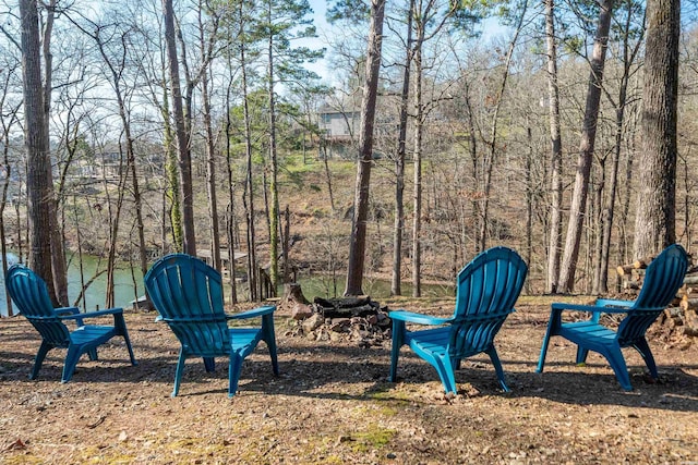 view of yard with a wooded view and an outdoor fire pit