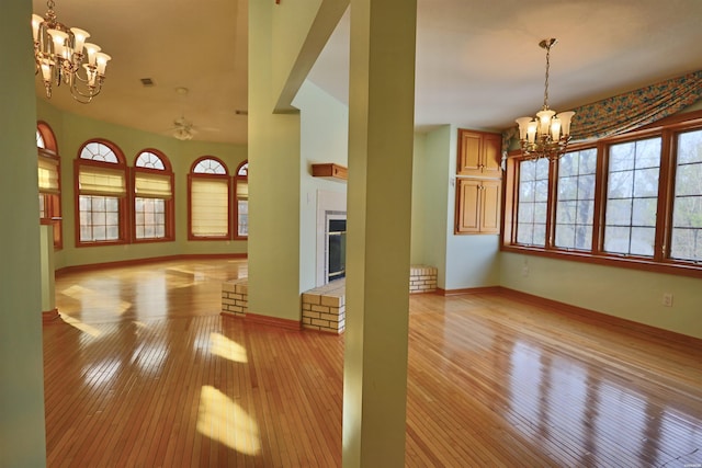 81 End Of Trail Rd, Mount Ida, AR 71957 - unfurnished living room with a chandelier, light wood-style floors, baseboards, and a brick fireplace