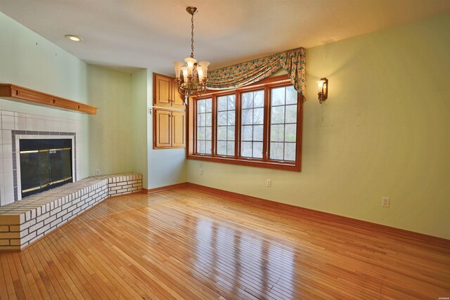81 End Of Trail Rd, Mount Ida, AR 71957 - unfurnished living room with light wood-style floors, a chandelier, and a glass covered fireplace