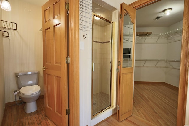 81 End Of Trail Rd, Mount Ida, AR 71957 - full bathroom with a stall shower, toilet, wood finished floors, baseboards, and a spacious closet
