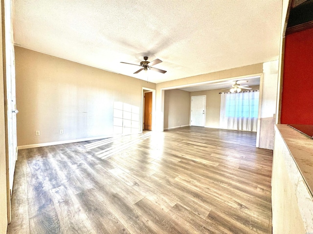 unfurnished room featuring ceiling fan, a textured ceiling, wood finished floors, and baseboards