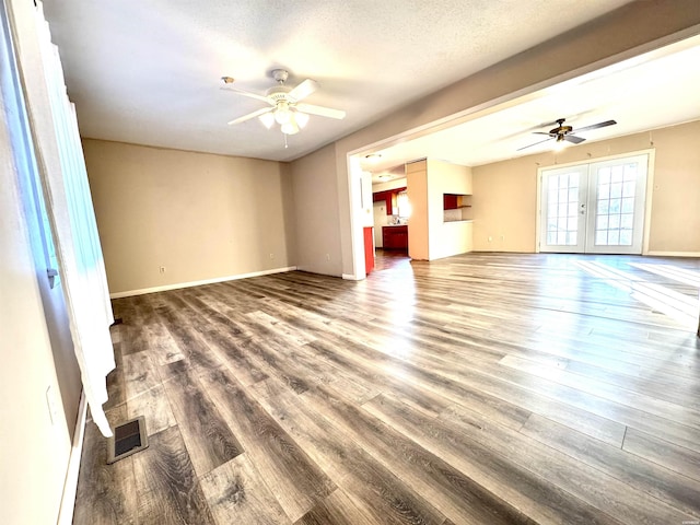 unfurnished living room featuring ceiling fan, french doors, dark wood-type flooring, and visible vents