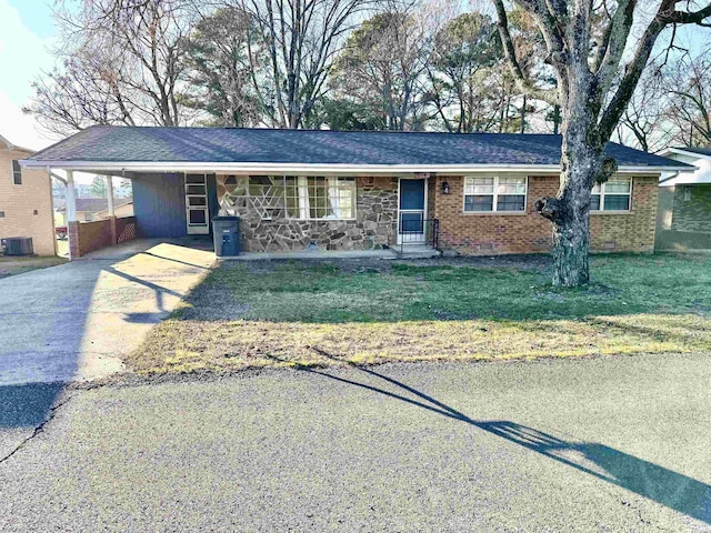 ranch-style home featuring brick siding, a front yard, crawl space, a carport, and driveway