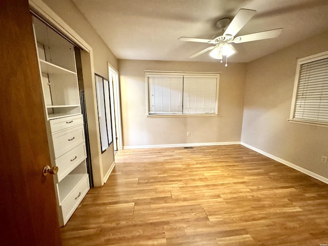 unfurnished bedroom with ceiling fan, light wood finished floors, and baseboards