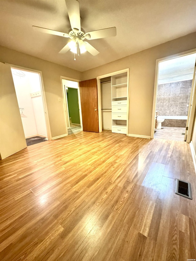 unfurnished bedroom featuring light wood-style floors, visible vents, a closet, and ensuite bathroom