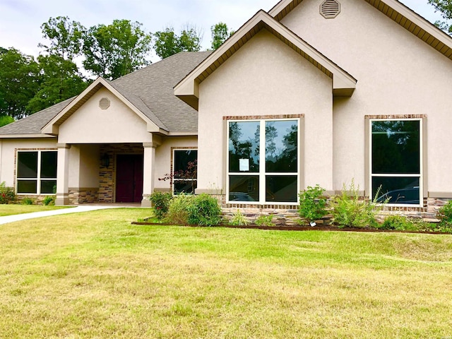 view of front of home with stone siding, stucco siding, and a front yard