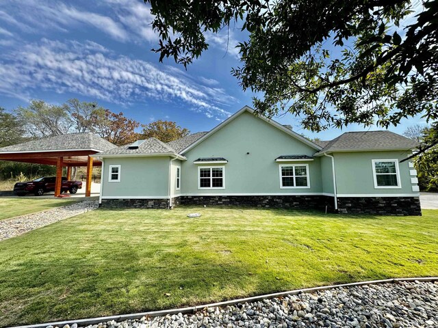 rear view of property with a yard, a carport, and stucco siding