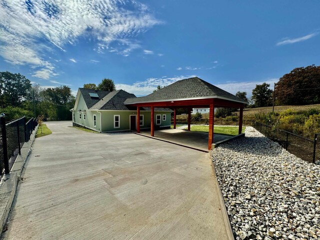 view of vehicle parking with driveway, fence, and an attached carport