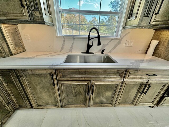 kitchen with light stone countertops, backsplash, and a sink