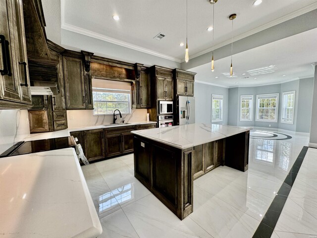 kitchen featuring a center island, pendant lighting, appliances with stainless steel finishes, a sink, and light stone countertops