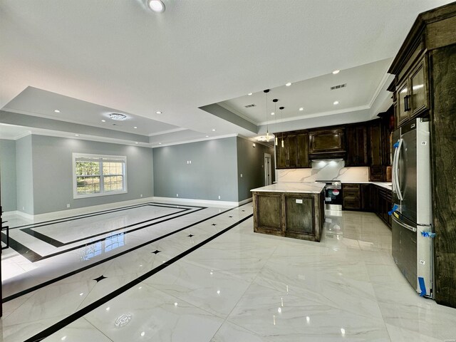 kitchen featuring baseboards, a kitchen island, appliances with stainless steel finishes, open floor plan, and a tray ceiling