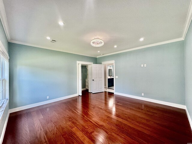 spare room with crown molding, dark wood-type flooring, and baseboards