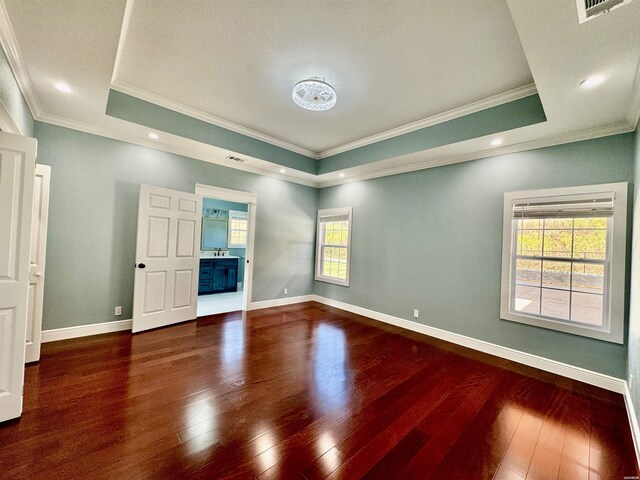 unfurnished room featuring ornamental molding, a tray ceiling, dark wood-type flooring, and baseboards