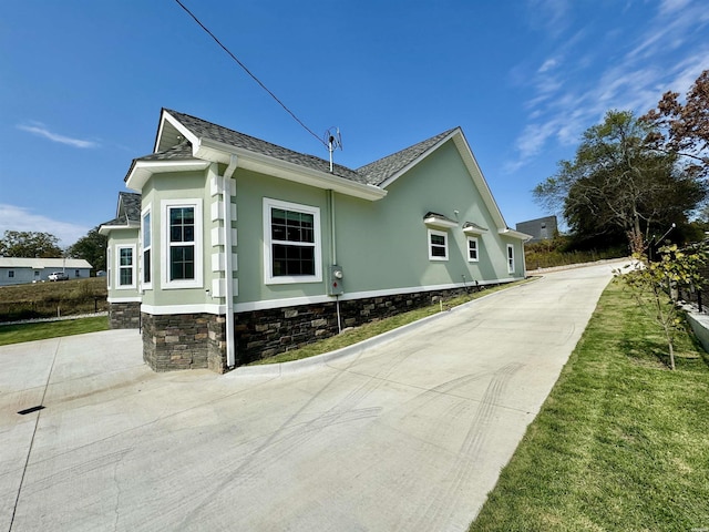 view of property exterior featuring a yard, a shingled roof, and stucco siding