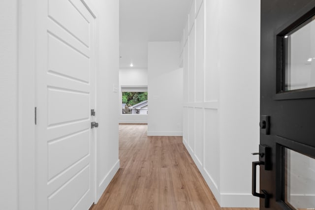 hallway featuring light wood-type flooring and baseboards