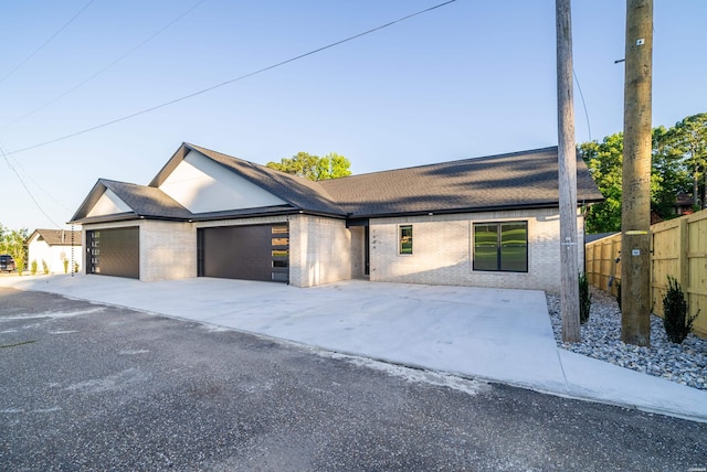 view of front facade with a garage, brick siding, and fence