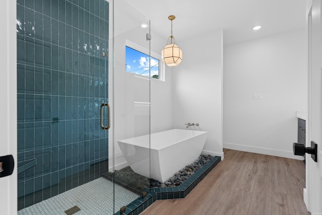 full bathroom with recessed lighting, wood finished floors, baseboards, a freestanding bath, and a shower stall