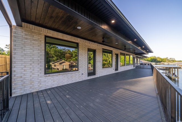 wooden terrace with a water view and ceiling fan