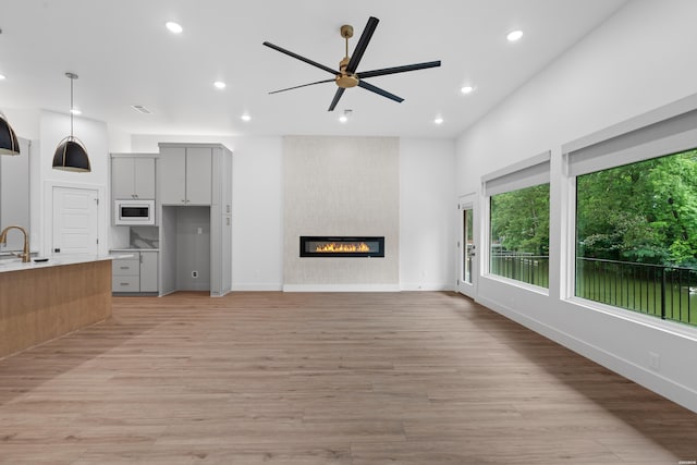 unfurnished living room featuring light wood-style floors, recessed lighting, a fireplace, and a ceiling fan