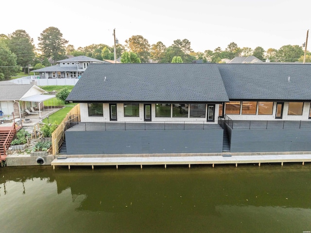 rear view of property featuring a shingled roof and a water view