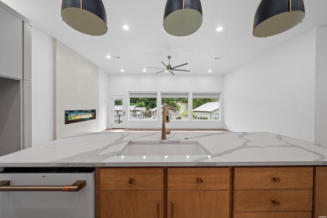 kitchen with a sink, light stone counters, open floor plan, and dishwasher