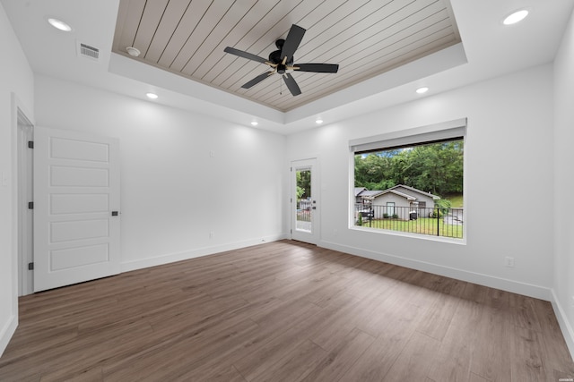 empty room with wooden ceiling, a raised ceiling, and wood finished floors