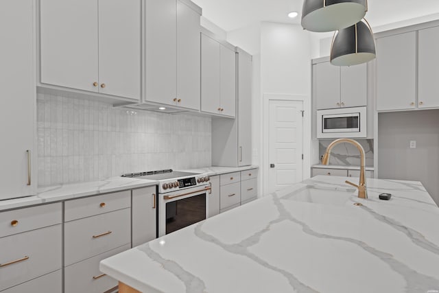 kitchen with white electric range, a sink, decorative light fixtures, and light stone countertops