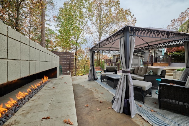 view of patio featuring fence, a gazebo, and an outdoor living space with a fireplace