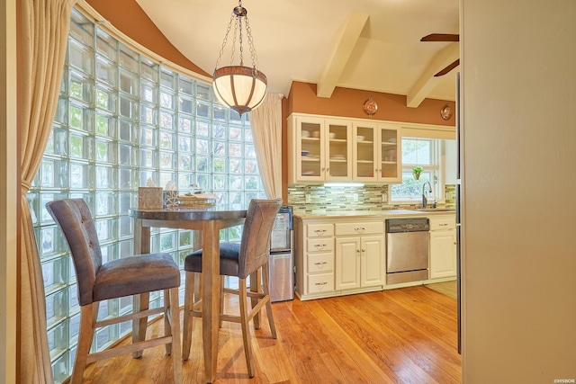 kitchen featuring light countertops, hanging light fixtures, stainless steel dishwasher, glass insert cabinets, and white cabinets